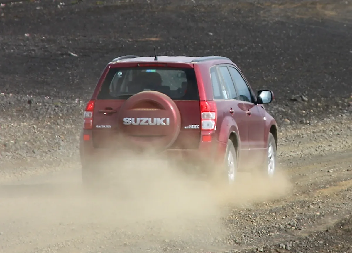 Illustrative photograph of a red four-wheel-drive vehicle on a dusty road; not a company vehicle